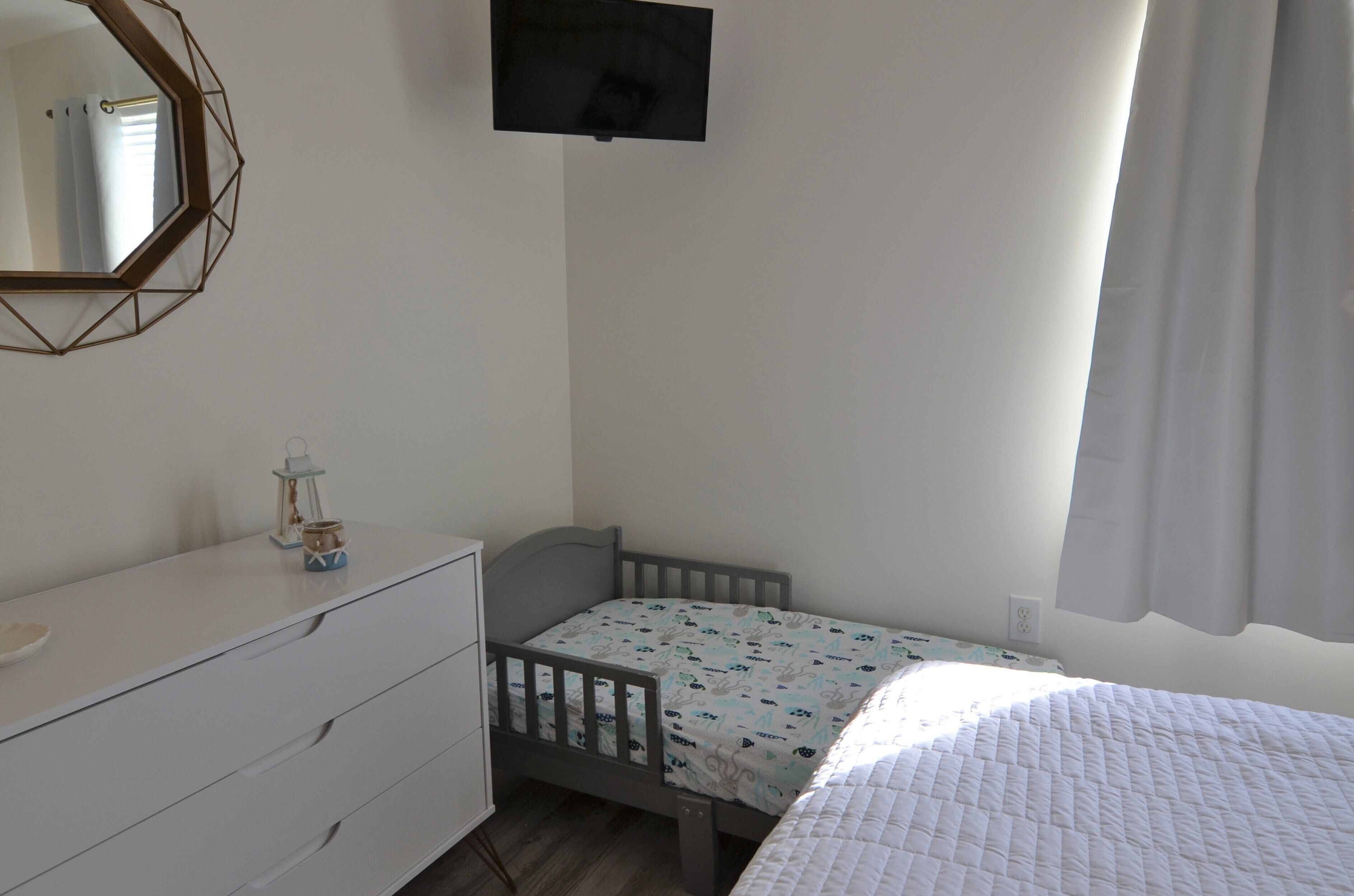 A child's bedroom with a bed, dresser, and a mirror.