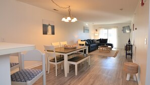 A dining area with a table and chairs, a sofa, and a television in a living room.