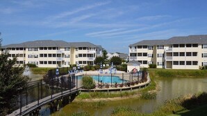 A multi-story hotel with a swimming pool and a bridge.