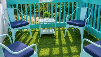 A turquoise outdoor seating area with two chairs and a small table, a sign indicating 'Beach', and a potted plant.