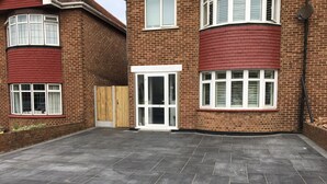 Una propiedad residencial con entrada pavimentada, portón de madera y fachada de ladrillo.