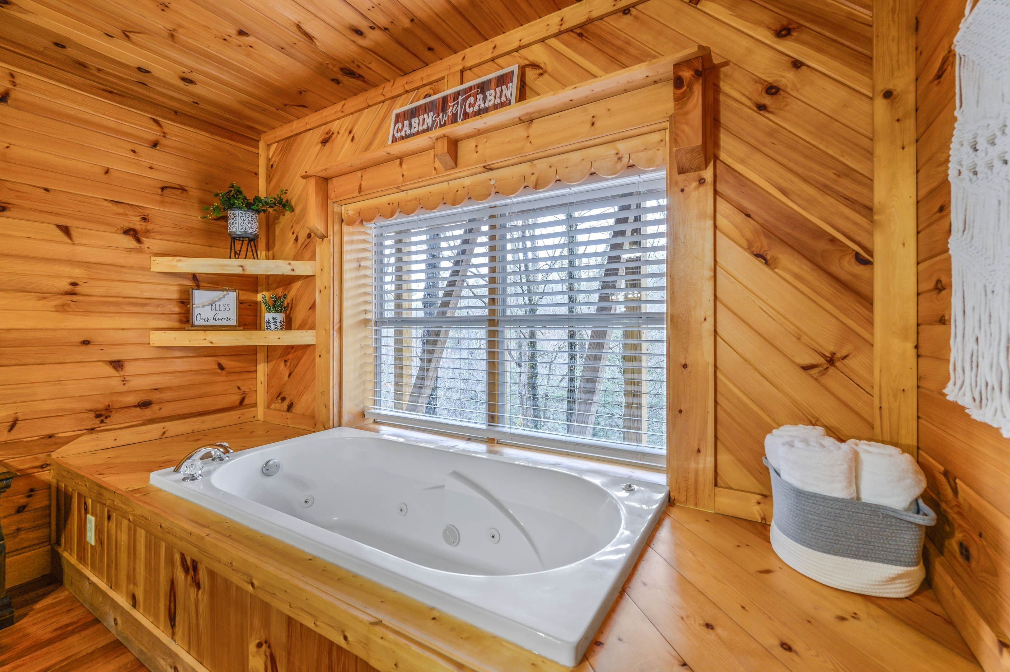 Interior de una cabaña de madera con una bañera grande, un cartel que dice "Cabin Cabin" y una ventana con persianas.