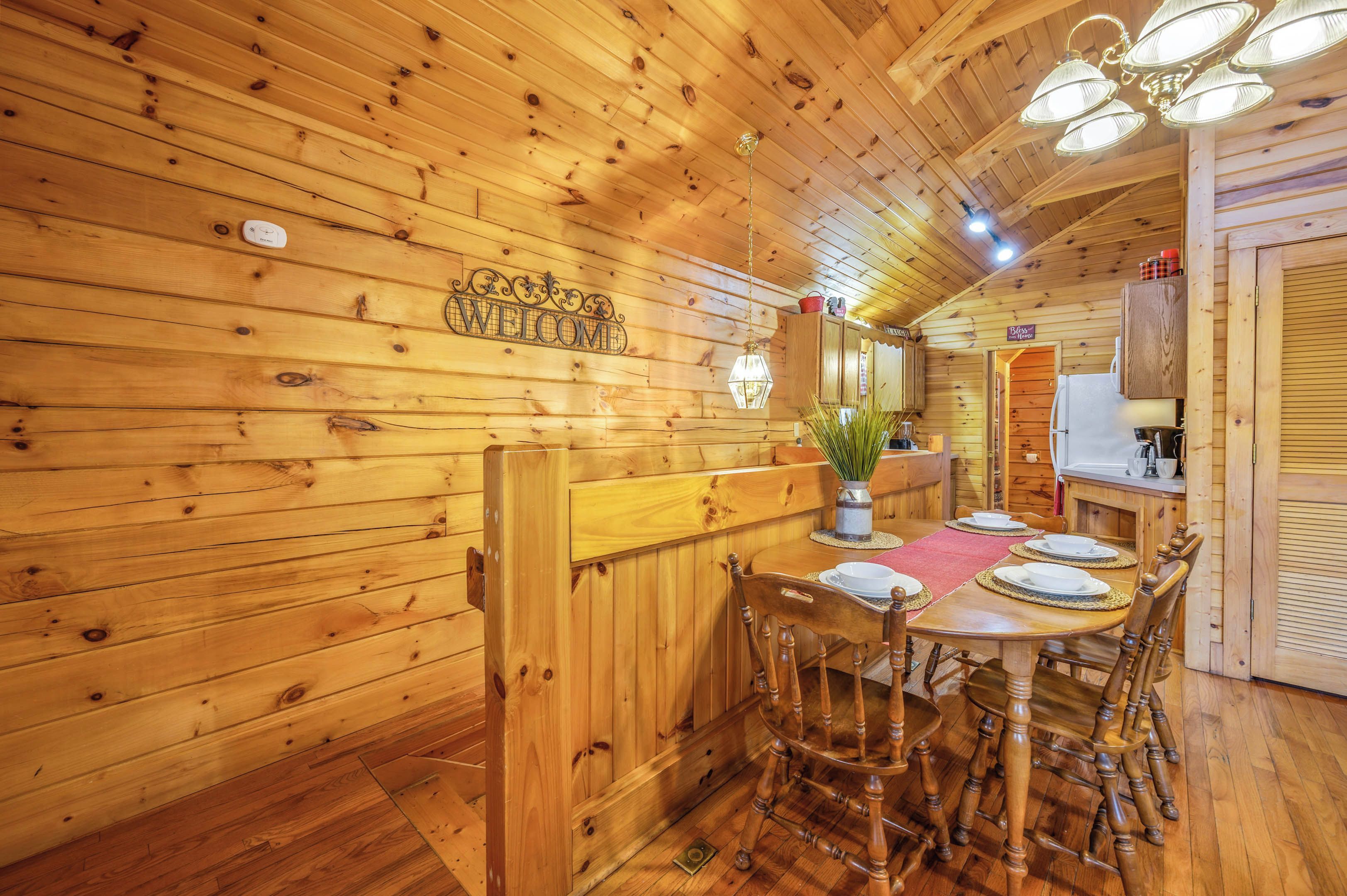 Interior de madera con una mesa de comedor para cuatro, un banco y una zona de cocina al fondo.