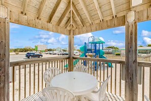 Relax in a serene gazebo with a covered seating area overlooking a playground with a slide and climbing structure.