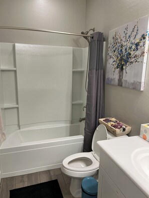 A bathroom with a bathtub, toilet, and a shower area.