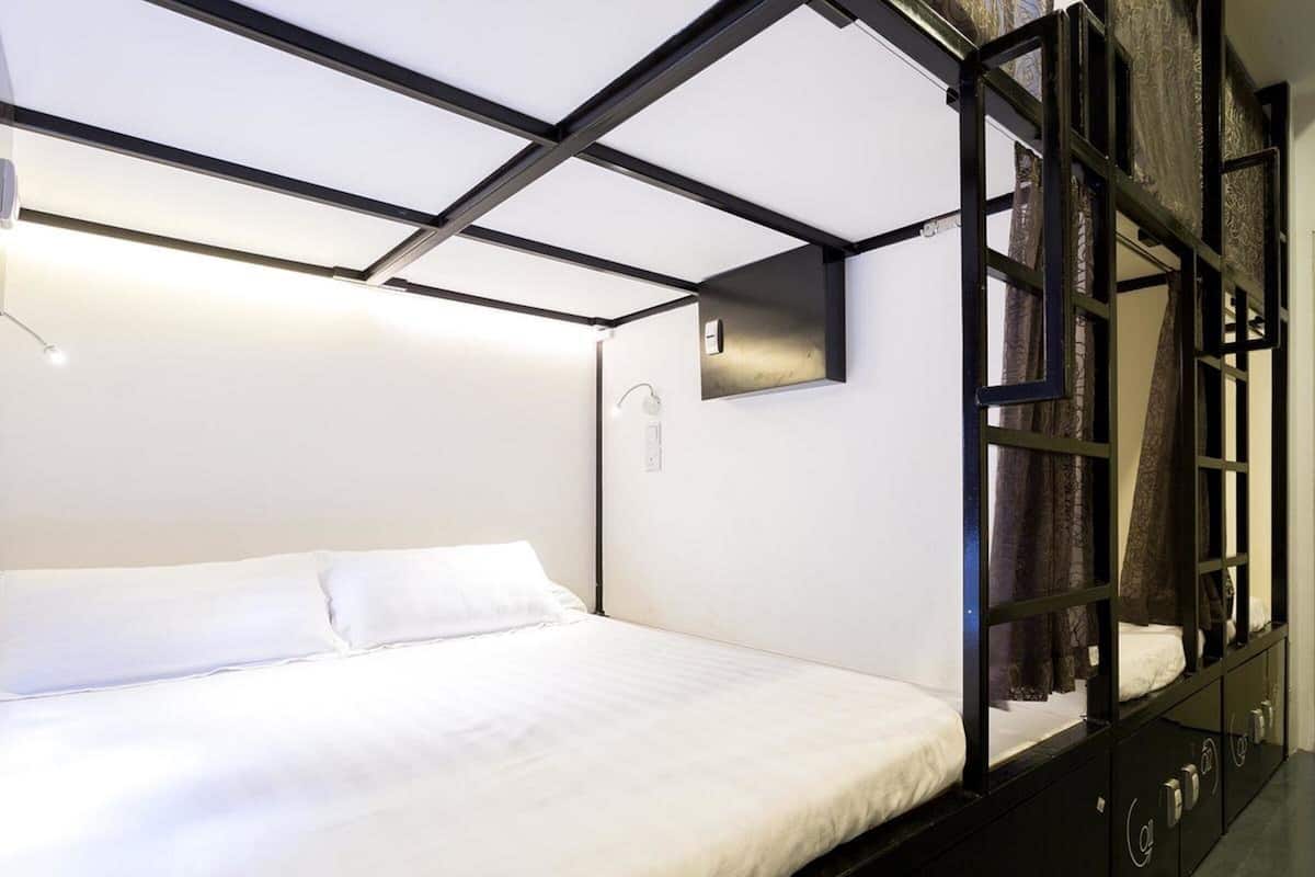A modern bedroom with a bed, a black wardrobe, and a mirror.