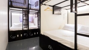 A bunk room with two beds, a hanging clothes rack, and a small window with patterned curtains. - K Space Inn Owen - Hostel (Singapore)