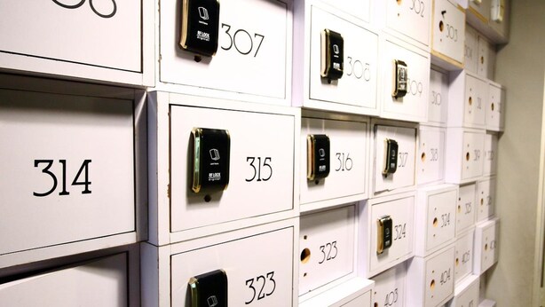 A wall of numbered storage boxes, each with a small electronic device on top. - K Space Inn Owen - Hostel (Singapore)