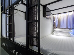 A bunk bed room with a window and curtains, a bedside table, and a wall-mounted light. - K Space Inn Owen - Hostel (Singapore)
