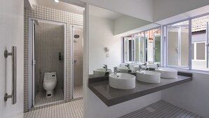 A modern bathroom with a walk-in shower, a toilet, and three sinks. - K Space Inn Owen - Hostel (Singapore)