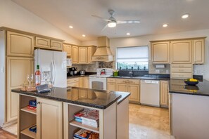 A spacious kitchen with light-colored cabinets, a central island, and a ceiling fan.