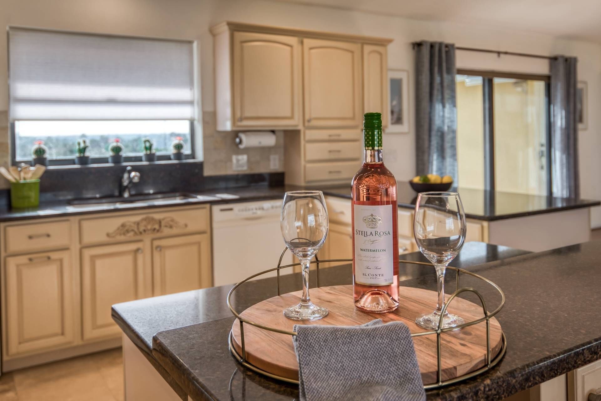 A kitchen with a wooden table, two wine glasses, and a bottle of Stella Rosa Watermelon wine.