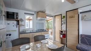 Una cocina compacta con comedor, microondas, refrigerador, estufa y un lavamanos pequeño.