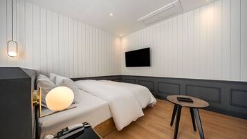 Una habitación de hotel moderna con una cama, una mesita de noche, una lámpara y un televisor de pared.