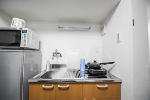 Una cocina compacta equipada con refrigerador, microondas, estufa y pileta.