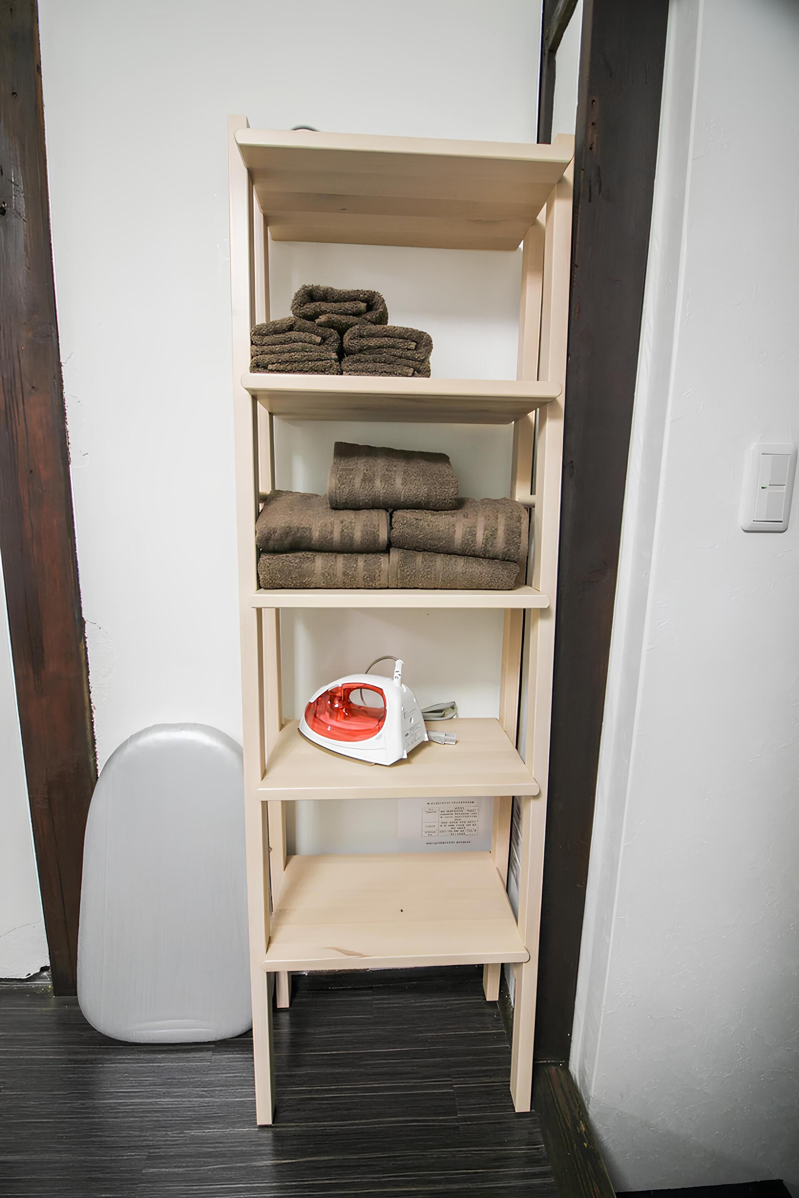 A wooden shelf unit with folded towels and a white appliance.