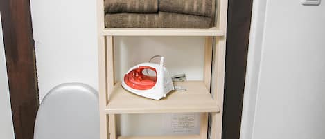 A wooden shelf unit with folded towels and a white appliance.