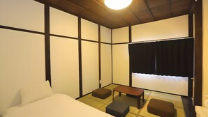 Quarto japonês tradicional com tatames, mesa de madeira baixa, sofá e futon.