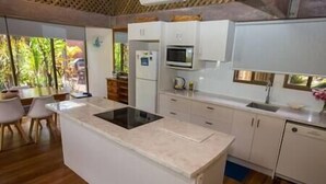 A modern kitchen with white cabinets, a central island, and a microwave. - Stay at 'Banfield 4' (Wongaling Beach)