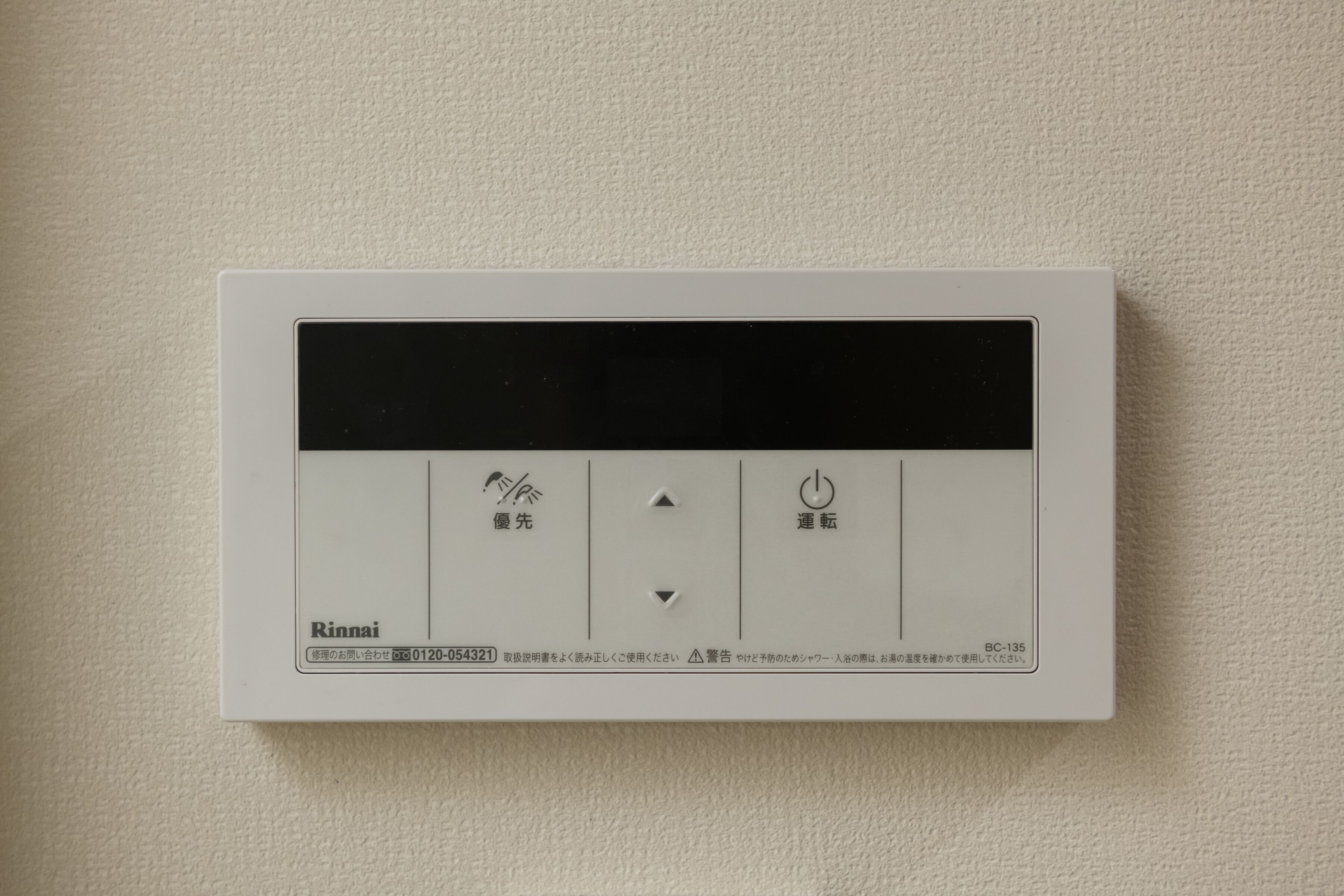 Een bedieningspaneel met Japanse tekst, een aan/uit-knop en een draaiknop voor temperatuurregeling.