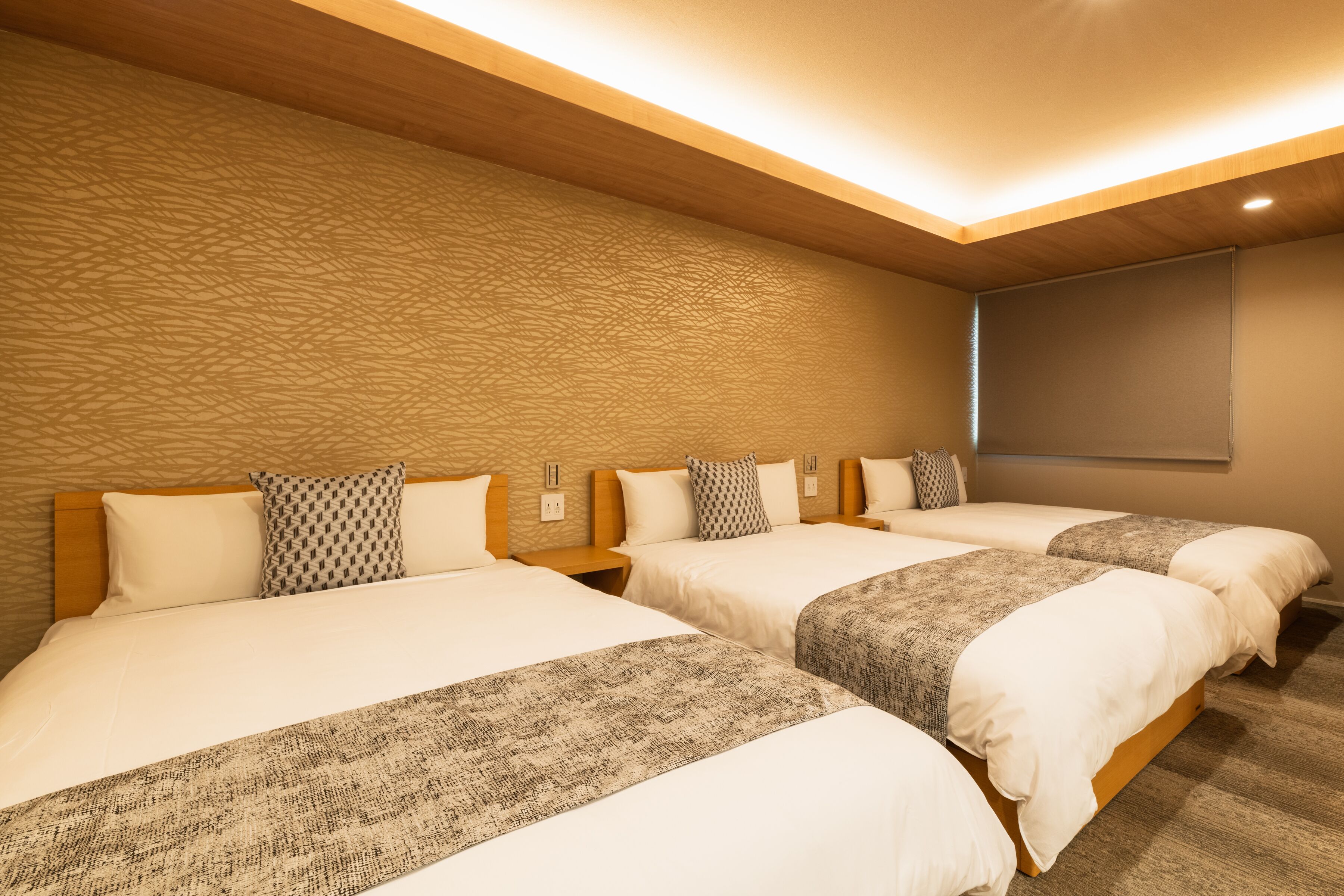 Habitación de hotel con dos camas y cabeceros de madera, y una pared con textura.