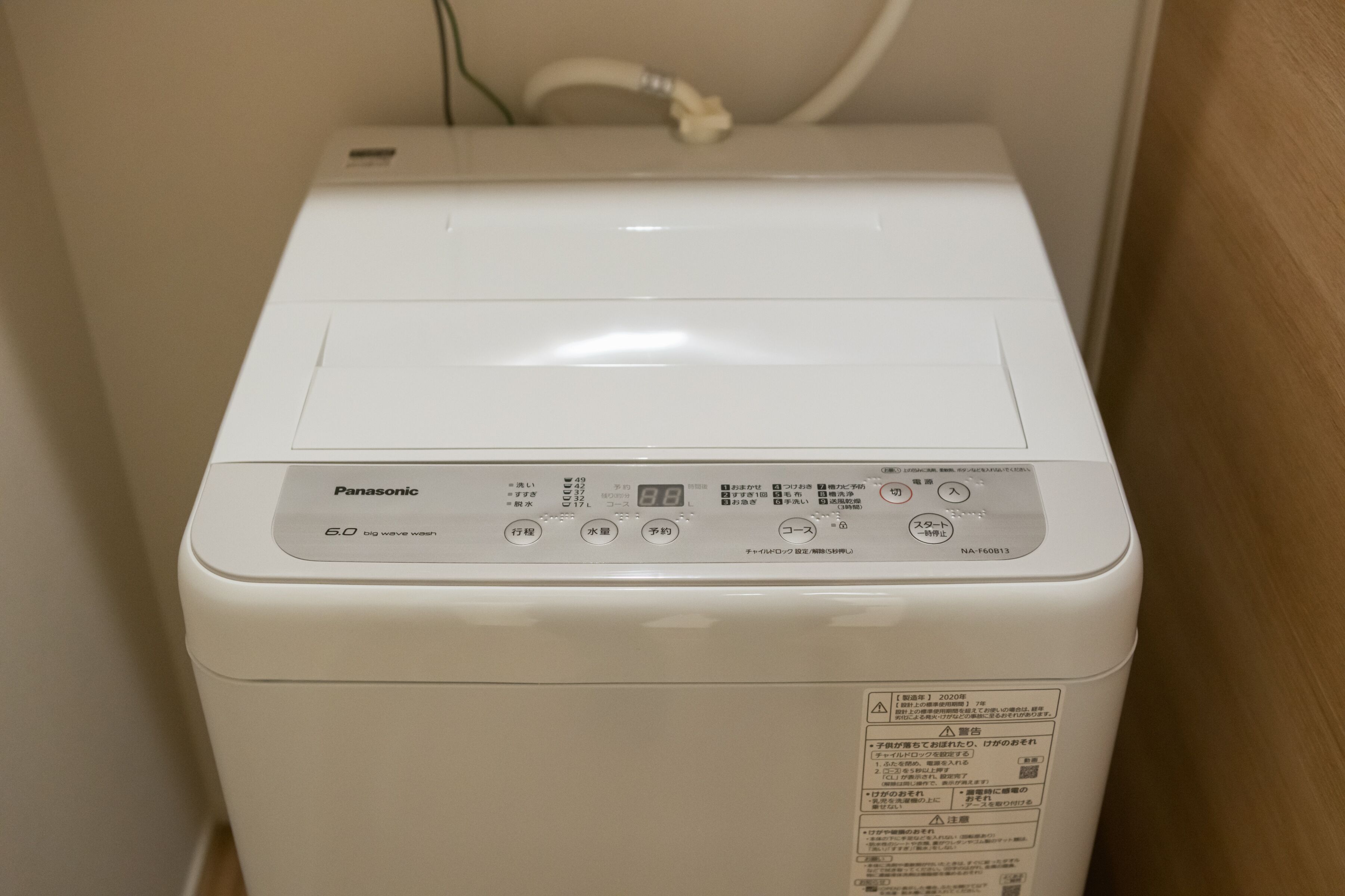 Une machine à laver Panasonic blanche, dotée d’un panneau de commande et d’une étiquette sur le côté.