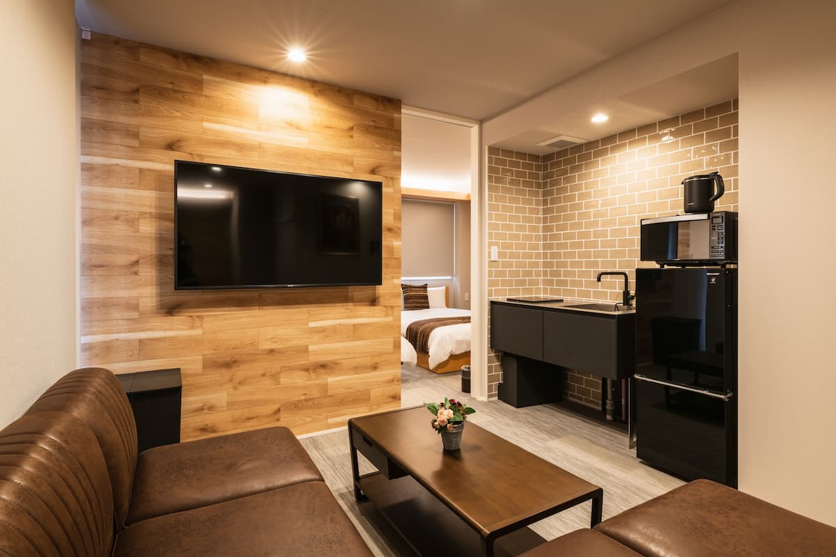 A modern living room with a flat-screen TV, a brown leather sofa, and a wooden accent wall.