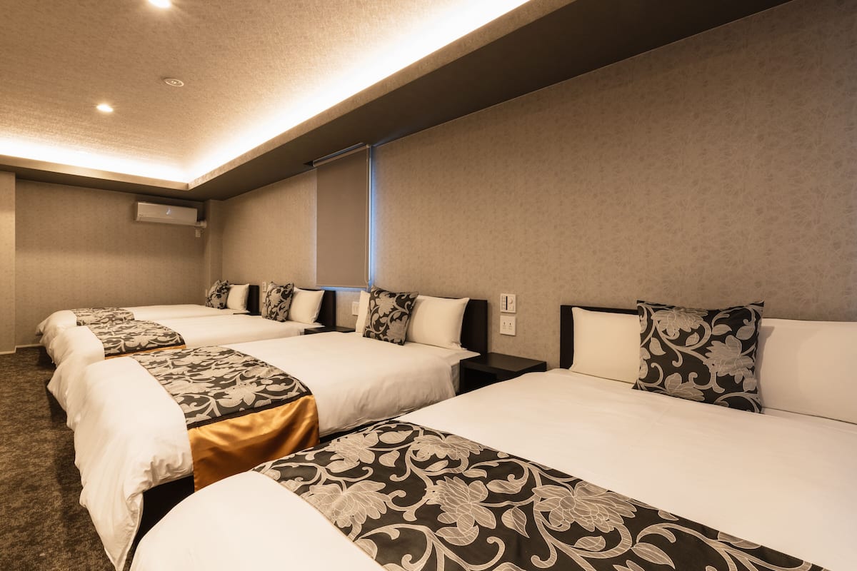 A hotel room with three beds, each with a patterned bedspread and matching pillows.