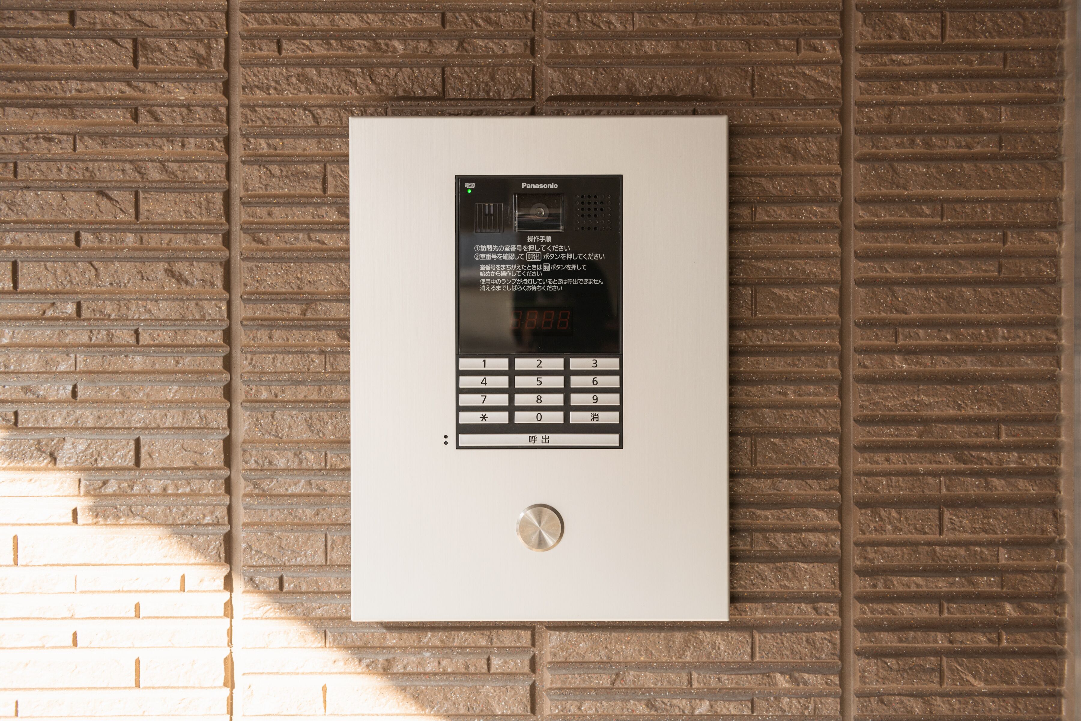 A wall-mounted elevator control panel with a digital keypad and instructions in Japanese.