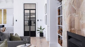 A modern living room with a stone fireplace, a wooden coffee table, and a grey sofa.