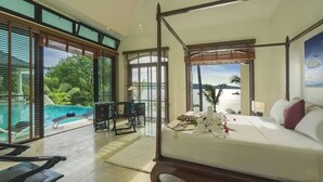 Amplia habitación con cama con dosel, vista al océano y zona de piscina visible a través de grandes puertas correderas.