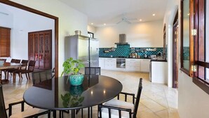 Una cocina moderna con una isla central, un comedor con una mesa redonda y un armario de madera tradicional.
