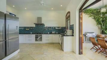 Uma cozinha moderna com frigorífico embutido, armários brancos e painel de azulejos.