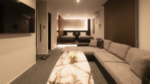 A modern living room with a large flat-screen TV, a marble coffee table, a beige sofa, and a large window. - GRAND BASE Hakata Premium (Fukuoka)
