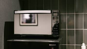 Un horno microondas Sharp sobre una encimera negra con salpicadero de azulejos.