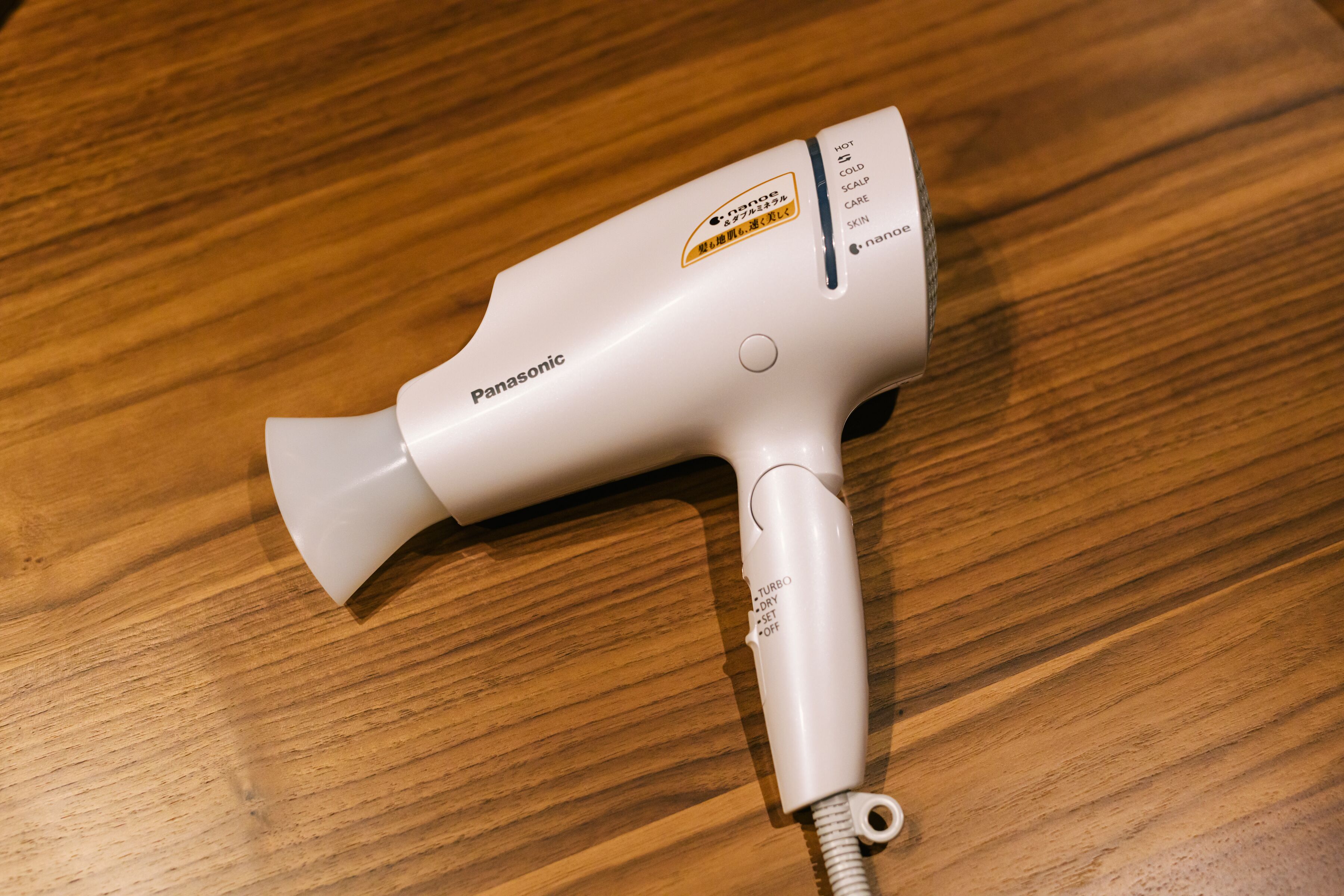 A Panasonic hair dryer on a wooden surface.