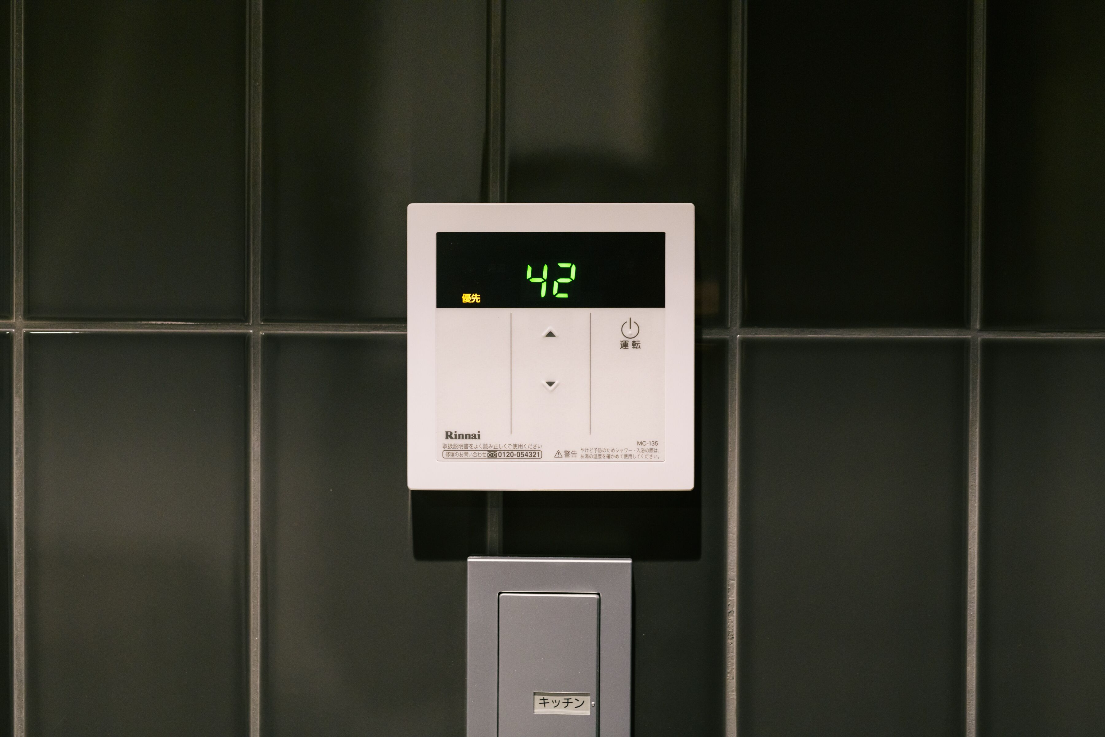 A digital thermostat displaying 42 degrees Celsius, a control panel, and a metallic box with Japanese text.