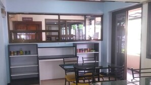 A dining area with a table and chairs, a kitchen area with cabinets and a counter, and a patterned floor. - Hotel Paraiso (Bangkok)
