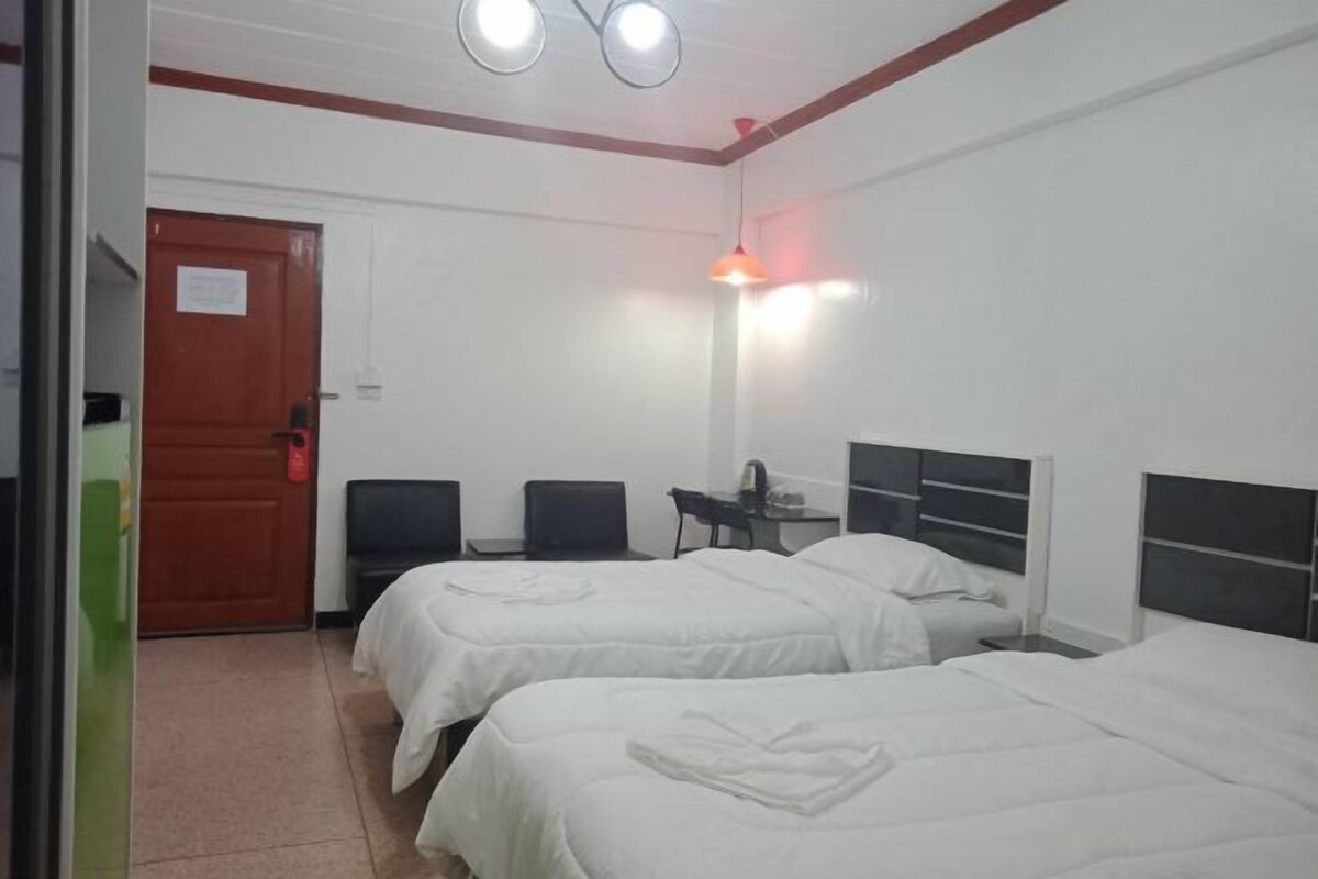 A hotel room with two beds, a desk, a chair, and a door.