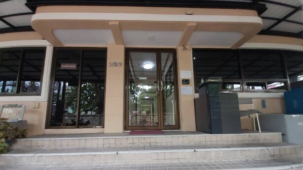 A building entrance with a glass door, a staircase leading up, and a small outdoor seating area with a table and chairs. - Hotel Paraiso (Bangkok)