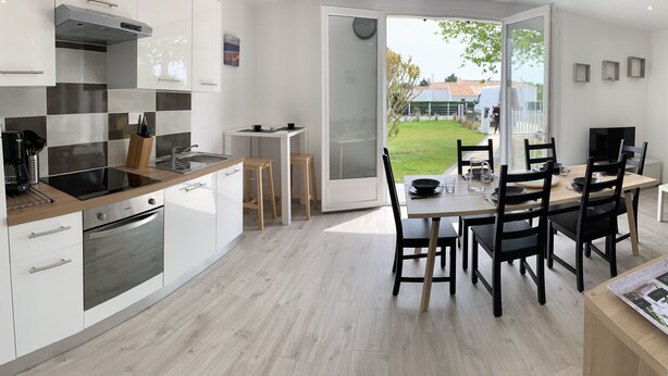 Eine moderne Küche mit weißen Schränken, einem eingebauten Backofen und einem Essbereich mit Tisch und Stühlen.