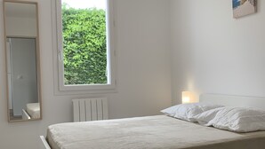Ein Schlafzimmer mit Bett, Fenster, Heizkörper, Spiegel und einem Bild an der Wand.