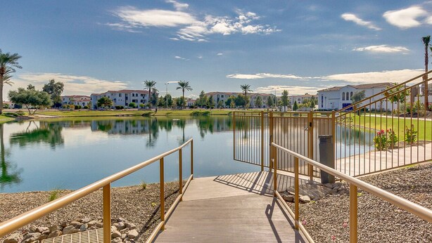 A waterfront view with a wooden deck leading to a lake, surrounded by buildings with a uniform architectural style. - Picture Perfect 2/2 with Views Galore! The Cays at Ocotillo! 30 Night Minimum Stay! (Chandler)