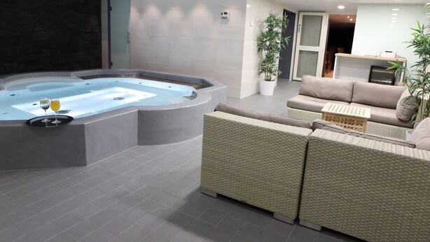 A modern indoor relaxation area with a hot tub, wicker furniture, and potted plants. - Hotel Fabrik Forssa (Forssa)