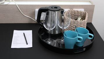 Uma bandeja preta com uma chaleira de aço inoxidável, duas taças de vinho e três canecas azuis sobre uma mesa preta.