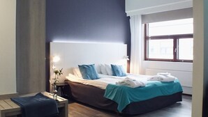 A modern bedroom with a large bed, bedside tables, a desk, and a window providing natural light. - Hotel Fabrik Forssa (Forssa)