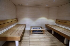 A sauna room with wooden benches and a bench seat in the center. - Hotel Fabrik Forssa (Forssa)