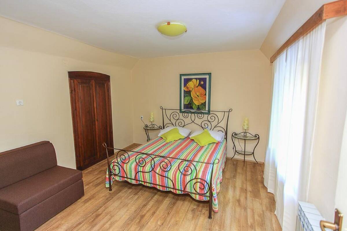 Ein Schlafzimmer mit einem Bett, einem Nachttisch, einer Lampe, einer Holztür und einem braunen Sofa.