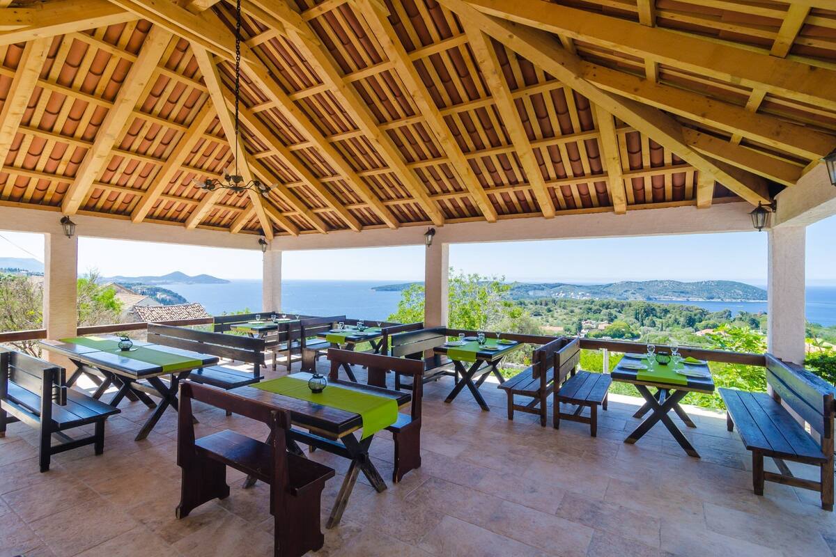 Eine Terrassengaststätte mit Holztischen und -bänken mit Blick auf eine malerische Landschaft.