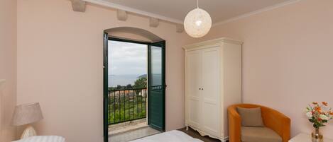 Une chambre à coucher comprenant un lit, une table de chevet, une chaise, une armoire et un balcon avec vue.